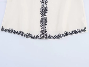 Close-up of contrast floral embroidery on beige shirt with white round buttons