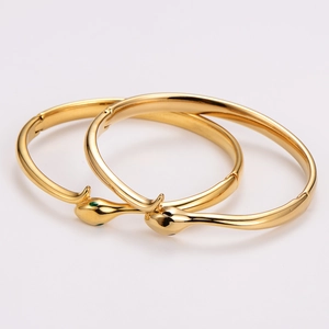 Polished 18K gold plated stainless steel snake bangle with green and black enamel eyes