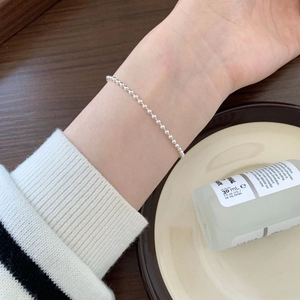 Model wearing a minimalist S925 silver beaded knot bracelet in a lifestyle setting