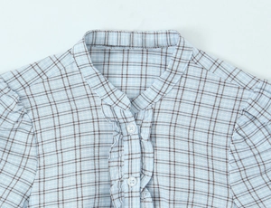 Detail of ruffled stand collar and white buttons on blue plaid short dress