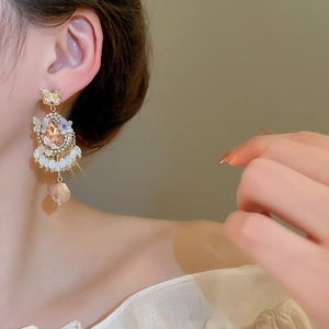 Close-up of vintage golden bow earrings with champagne teardrop crystal worn by model