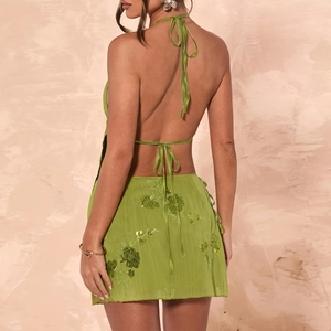 Detail of green sequin mini dress featuring an open back and halter neck tie closure