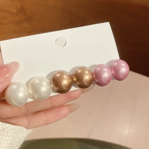 Close-up of elegant pearl hair clip featuring white, champagne, and purple beads