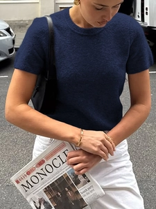 Détail d'un haut en maille bleu marine à manches courtes porté avec un sac baguette noir chic