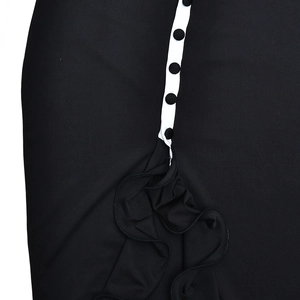 Detail view of the black dress featuring a white button placket and elegant ruffled hem