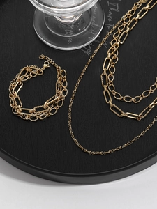 Detailed view of layered 18k gold-plated stainless steel paperclip chain necklace and bracelet