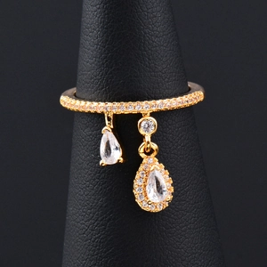 Elegant gold-tone stacking ring with teardrop zircon pendants on a black display stand