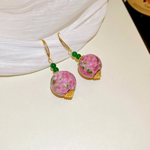 Close-up of pink and green ceramic bead earrings with gold-plated rhinestone hooks