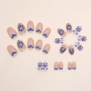 Short oval press-on nails in nude pink with vibrant royal blue floral patterns