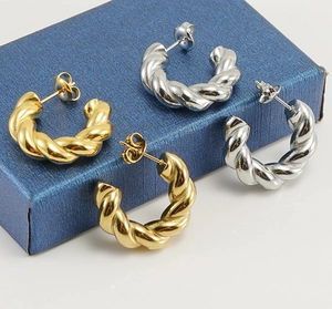 Makroaufnahme von gedrehten Creolen in Gold und Silber auf einer blauen Geschenkbox