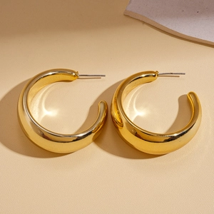 Detailed view of large gold-tone C-shape hoop earrings with a polished metallic finish