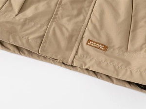 Detailed close-up of khaki windbreaker hem with high-quality stitching and decorative label