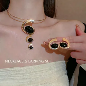 Golden swirl jewelry set featuring black oval resin necklace and matching earrings