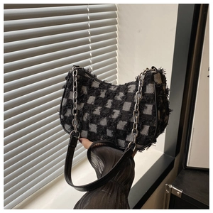 Detail of checkered tweed crossbody bag with silver chain strap and frayed fringe edge