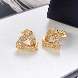 Macro shot of gold geometric triangle stud earrings with shimmering pavé crystal accents