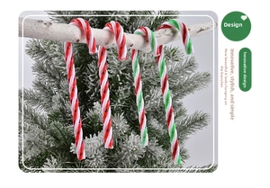 Close-up of red, white and green candy cane ornaments on a snowy Christmas tree
