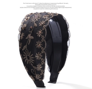 Detalle de diadema ancha negra con bordado floral dorado y cuentas de cristal brillantes
