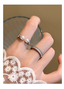 Close-up of stacked silver rings with imitation pearls and cubic zirconia on a hand