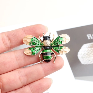 Macro shot of bee brooch with green enamel wings and gold alloy frame details