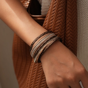 Gros plan d'un bracelet multicouche en cuir avec croix et strass sur le poignet d'une femme