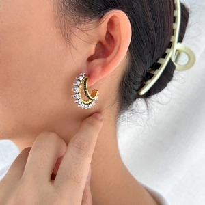 Elegant 18K gold-plated C-shaped earrings with white zircon and green crystals on model
