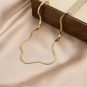 Detailed view of golden herringbone flat snake chain on champagne satin and wooden box