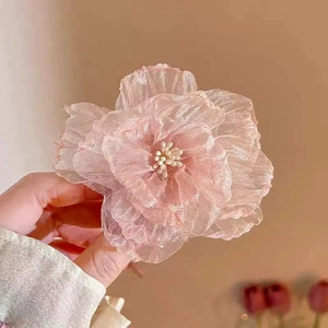 Close-up of a pink organza flower hair clip with layered petals and white stamen detail