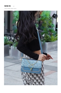 Detail of blue glitter shoulder bag with golden heart clasp and stylish chain strap