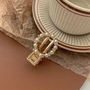 Detail of vintage gold pearl hair clip with rhinestones on a minimalist aesthetic background
