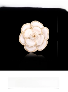 Détail de broche camélia avec bords dorés et perles, taille 45mm sur fond noir