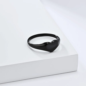 Minimalist black heart-shaped titanium steel ring on elegant white geometric stand