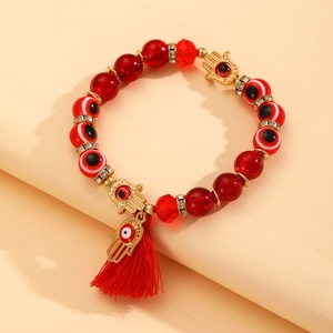 Detail van rode kralenarmband met Hamsa-bedel, Evil Eye-kralen en een zijden kwast