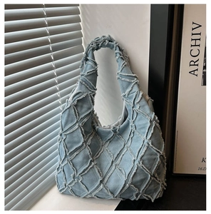 Detail of light blue denim hobo bag featuring quilted diamond stitching and raw frayed edges