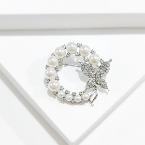 Detailed view of elegant wreath brooch with pearls and zircon butterfly on white steps