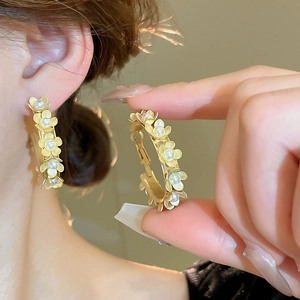 Detailed view of floral hoop earrings featuring gold petals and white pearl centers