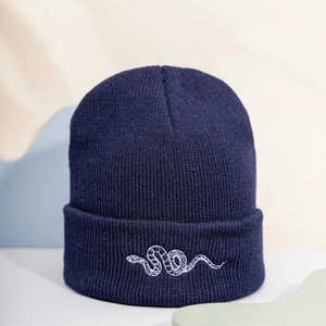 Dark blue knitted beanie featuring a white snake embroidery on a textured cuff