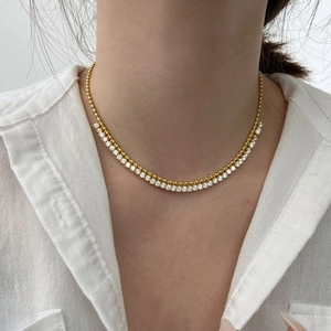 Close-up of a gold olive leaf tassel necklace with sparkling white zircons on a model