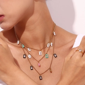 Close-up of layered gold necklaces with colorful enamel pendants and zircon stone details