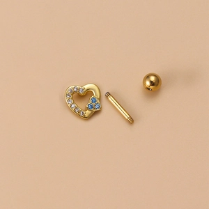 Detail of gold heart tragus piercing with blue and white zircons and screw ball back