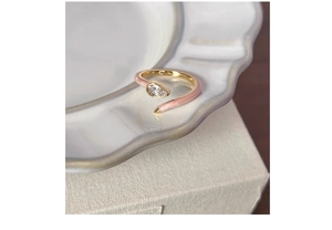Detailed macro of pink enamel band and teardrop-shaped gemstone on open silver ring