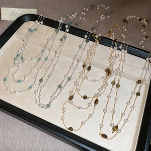Dettaglio delle collane in oro e argento con perle e pietre occhio di tigre su vassoio