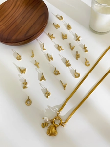 Detail of gold heart pendant and pearl on stainless steel letter necklace set