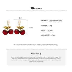 Détail des boucles d'oreilles cerise avec fruits en résine rouge et feuilles en zircon