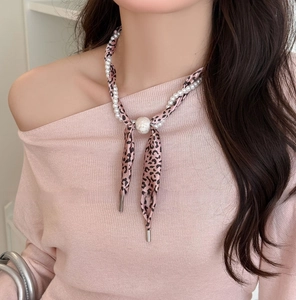 Detail of French vintage pearl necklace with pink leopard print silk scarf on model