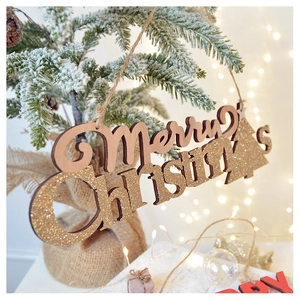 Close-up of wooden Merry Christmas star ornament hanging on a snowy pine branch