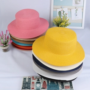 Top view of stacked colorful flat top straw hats in various vibrant summer colors