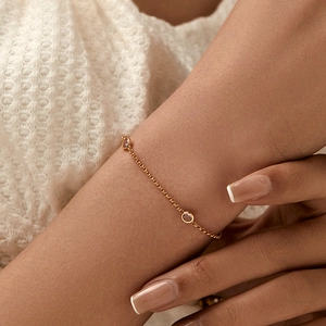 Pulsera de cadena dorada minimalista con circonitas esmeralda redondas en la muñeca