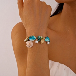 Dettaglio macro del bracciale oceano con conchiglie blu, perle e ciondoli dorati