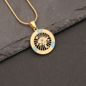 Detailed macro view of gold evil eye pendant necklace with blue enamel on stone surface