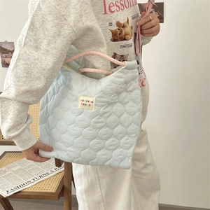 Détail du sac fourre-tout matelassé bleu clair avec anses tissées roses et logo design
